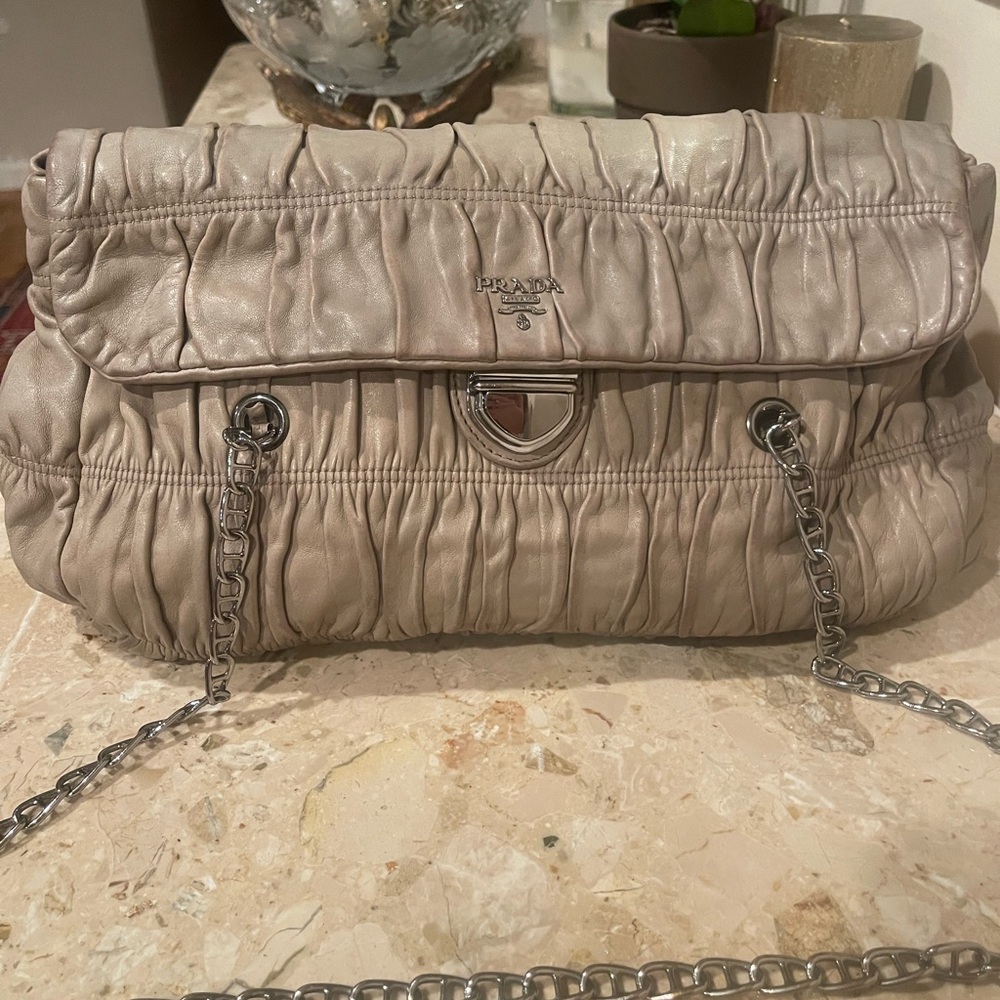Authentic Prada Cream Shoulder Bag with Metallic Logo and Satin Texture.